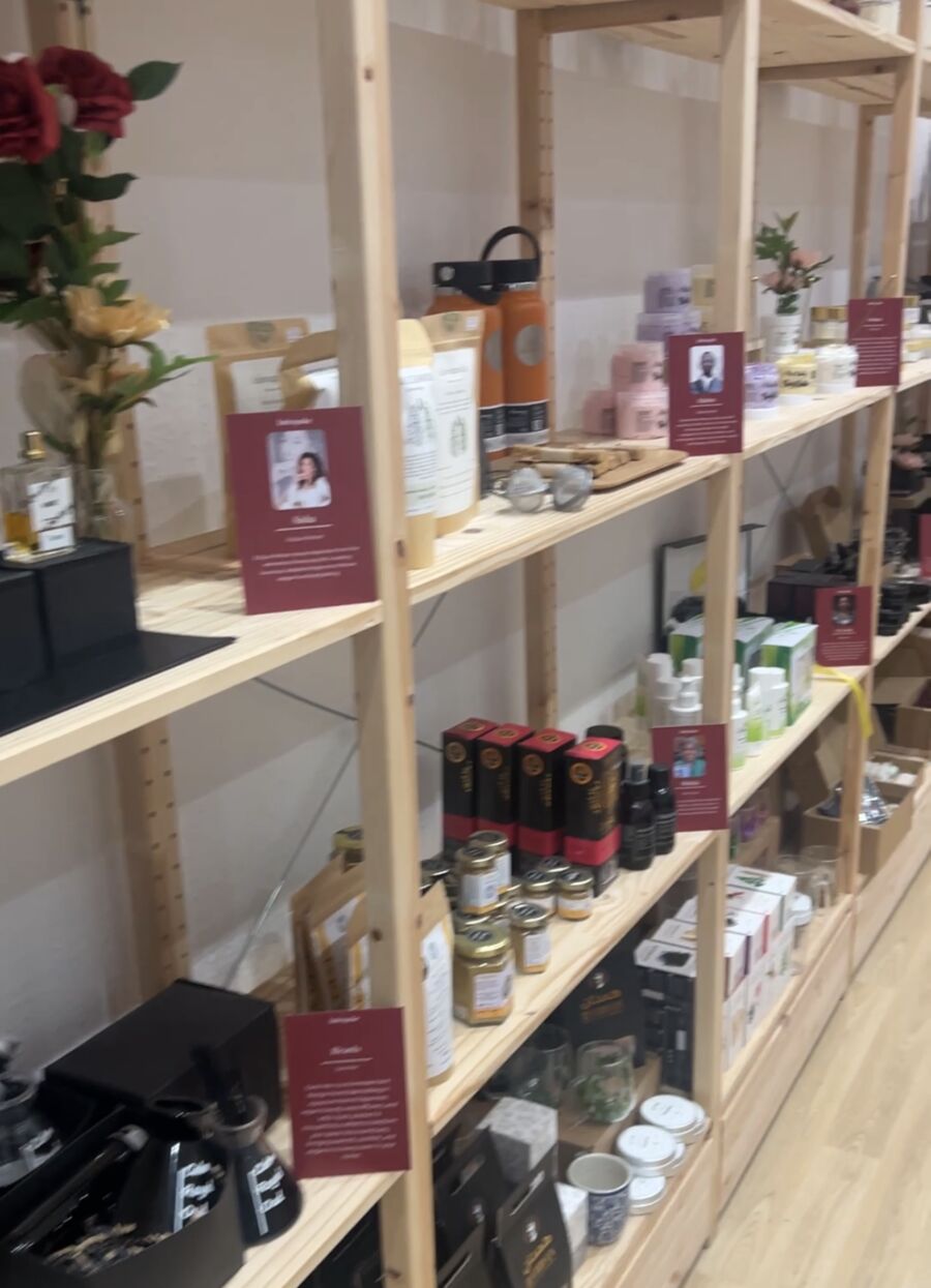 Indespoke shelves with burgundy A6 cards standing next to each brand's products. Each card has the brand owner's headshot, their name and a short paragraph about them.